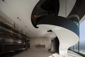 A modern lobby with glass spiral staircase, black and white color scheme, and minimalist design elements.