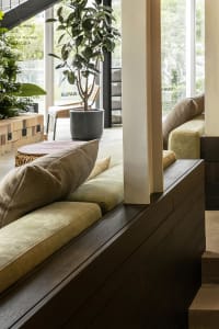 Modern living room with wooden furniture and potted plants, featuring soft lighting and cozy seating area.