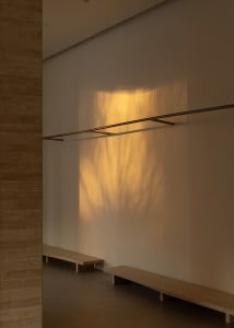 A minimalist interior with a metal lamp casting a shadow on a wall.