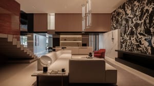 Modern living room with marble walls and floor, featuring a sleek sofa, coffee table, and red armchair.