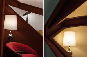 A modern interior design featuring a wooden staircase with a lamp and a red chair.