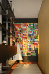 A brightly colored, abstract wall mural in a modern entrance hall with a wooden floor and shelving unit.