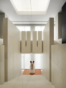 A modern interior design featuring concrete and wood stairs with natural light and high ceilings.