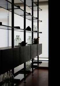 Modern minimalist bar with glass shelves and bottles arranged methodically.