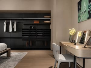 A modern, minimalist bedroom featuring wooden furniture, a sleek dresser, and a large mirror.