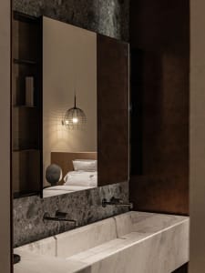 Modern bathroom with a white marble sink and a black wire pendant light hanging above a mirror.