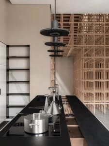 Modern minimalist kitchen with steel countertops, stainless steel cookware, and wooden shelving.