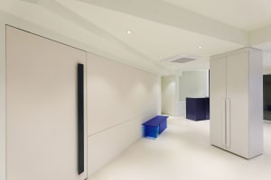 Modern minimalist office with white painted walls and floors, featuring sleek furniture and contemporary design.