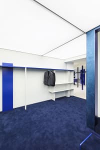 A modern closet with white walls, blue flooring, and a metal storage system.
