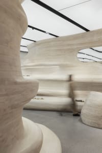 Modern interior with wooden curved structures and a person walking through the space.