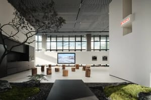 A modern kitchen exhibition room featuring wood stools and a large screen displaying a snowy landscape.