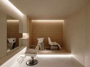 Modern salon interior with concrete tiles, minimalist white chairs, and sleek design elements.