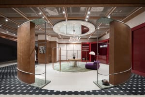 A modern retail store interior with metal and wood finishes, featuring a circular central area with a chandelier and a purple