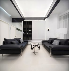 A modern living room with black leather sofas, a glass coffee table, and a minimalist glass sculpture.