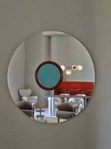 A modern interior design featuring a round mirror with a metal frame, reflecting a contemporary space with furniture and ligh