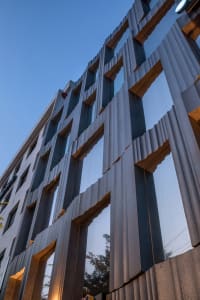 Modern metal building façade with geometric patterns against a blue sky.