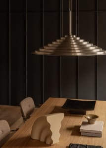 Modern minimalist metal table with geometric design, featuring dark brown wood surface, black plate, gold bowl, and surreal a