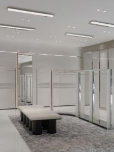 A minimalist retail interior with glass cabinets and a white bench.