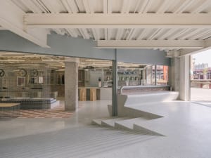 A modern, industrial-style coffee shop with concrete and terrazzo flooring.