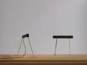 A modern desk lamp with a marble base, lying flat on a wooden surface.