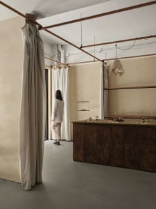 A minimalist interior space featuring fabric blinds hanging from a ceiling rail to create privacy and light control.