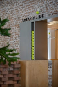 A modern industrial interior with brick walls and concrete finishes, featuring a tennis ball dispenser.