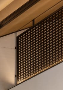 Modern interior with a metal grid wall and wooden ceiling beams.