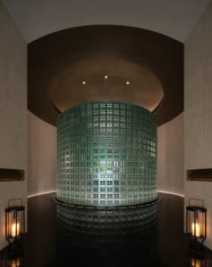 A modern spa interior with a cylindrical glass block wall, illuminated from within.