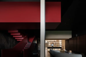 A modern living room featuring a metal staircase with red wall panels next to it.