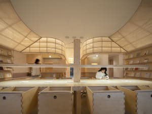 A modern library interior with wooden elements and light-colored fabric ceilings.