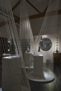 A contemporary museum exhibit featuring hanging fabric textile installations and sculptures.