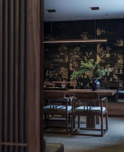A modern living room with sleek, minimalist furniture made from dark wood and adorned with plush textiles and decorative elem