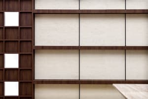 Modern, minimalist bookshelf with wooden shelves against a textured wall background.