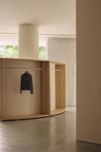 A modern, minimalist wardrobe with curved walls and a single shirt hanging on it.