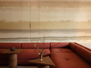 Lounge room with soft, terracotta-colored sofa and side tables, featuring an abstract background wall.