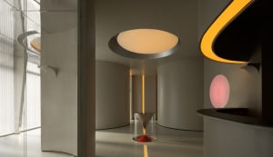 A modern interior space with a concrete floor, circular lighting feature, and minimalist design.