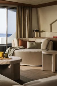 Modern living room with a neutral color palette, featuring a round sofa, round side tables, and a large window overlooking th
