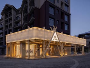 An illuminated retail storefront with glass walls, wooden accents, and warm lighting.