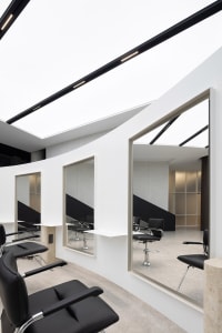 A modern minimalist hair salon with black and white color scheme and metallic black furniture.