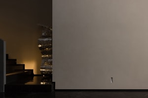 A minimalist interior space featuring a metal staircase with reflective surfaces.