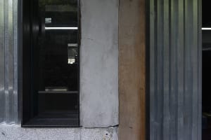 A close-up of a modern architectural window with a concrete wall and wooden and aluminum framing.