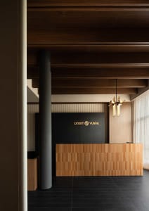 An industrial style office reception desk and counter made of wood tiles with a sign displaying 'LVXSIT YUSPA'.