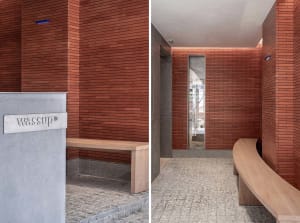 A modern lobby with red brick walls and a wooden seating area.