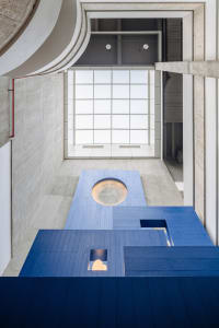 Modern interior space with concrete flooring and a circular opening, illuminated by warm lighting.