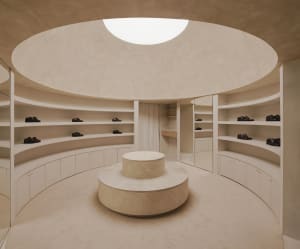 A modern circular closet with granite columns, featuring a central pedestal and shelves lined with black shoes.
