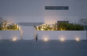 A modern exterior building facade with concrete walls and glowing lights at dusk.