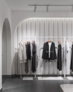 Modern minimalist clothing retail store with metal frames and clothing racks.