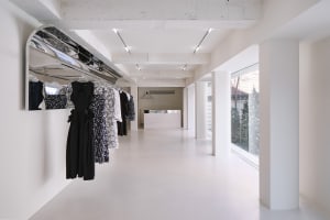 Modern retail clothing shop with concrete floor, glass windows, and steel rails