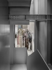 A modern clothing store interior with dark metallic elements and concrete walls.