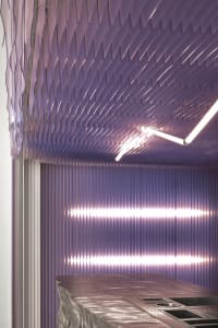 Modern interior design featuring a metallic surface with geometric patterns and industrial lighting.